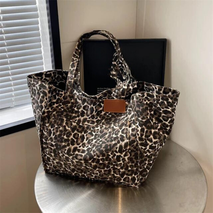 "Stilren damoversized axelväska i leopardmönstrad canvas med stora fickor, perfekt accessoar för en djärv och praktisk look."