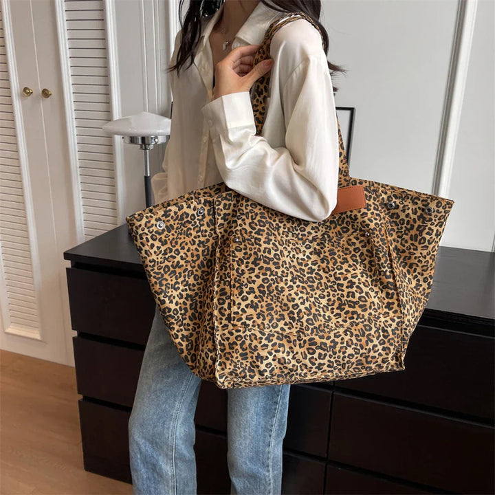 "Stilren damoversized axelväska i leopardmönstrad canvas med stora fickor, perfekt accessoar för en djärv och praktisk look."
