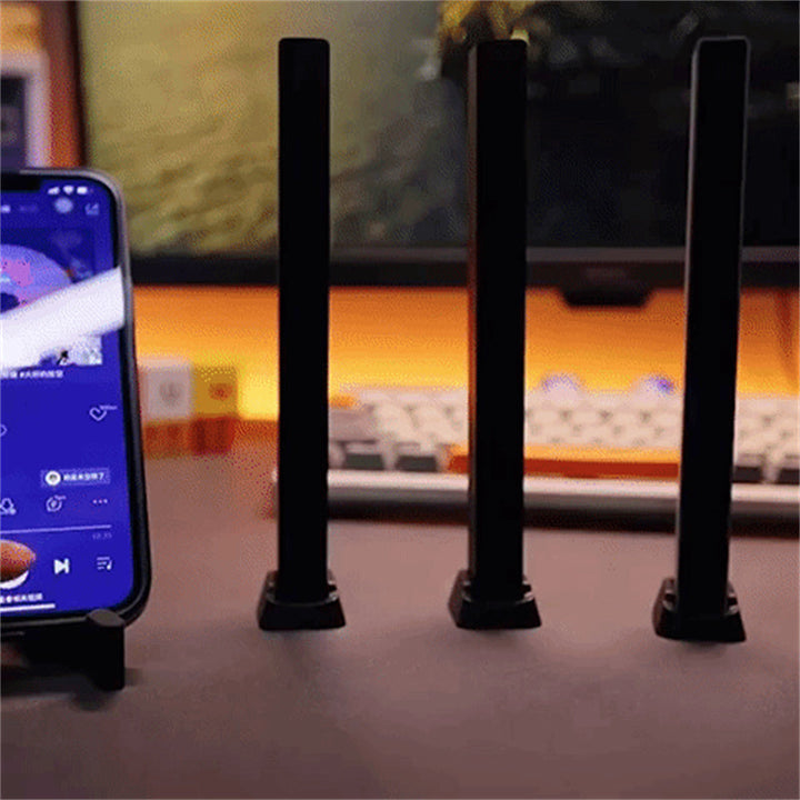 "Trådlös ljudaktiverad RGB ljuslist i svart, reagerar på musik med färgat sken och skapar dynamisk atmosfär."