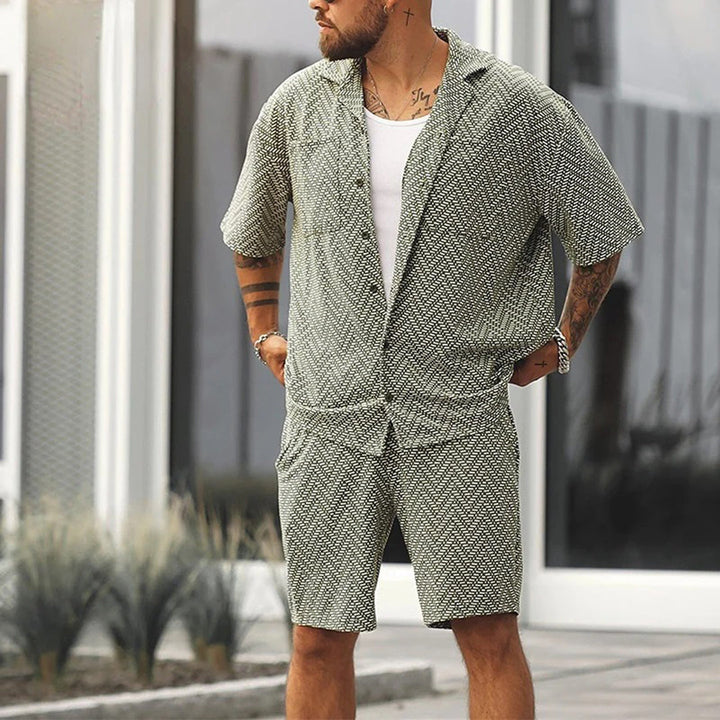 "Tvådelat herrset i mjukt grönt material, kortärmad skjorta med fickor och matchande shorts, perfekt för sommar."