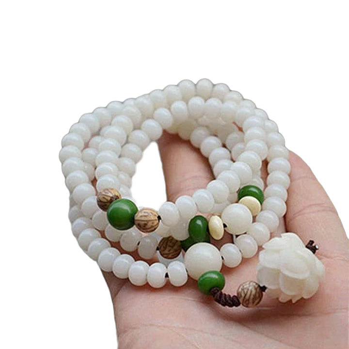 "Unisex Bodhi armband med vita Bodhi-frön och lotusblomma, främjar lugn och meditation, elegant design."