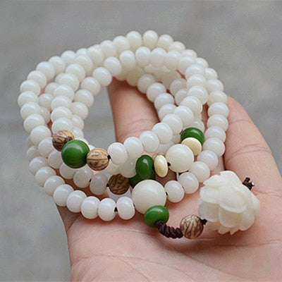 "Unisex Bodhi armband med vita Bodhi-frön och lotusblomma, främjar lugn och meditation, elegant design."