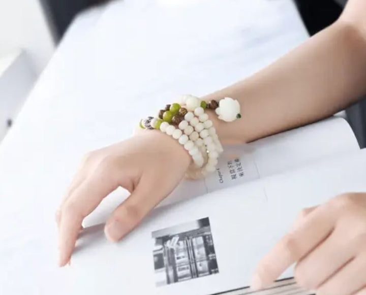 "Unisex Bodhi armband med vita Bodhi-frön och lotusblomma, främjar lugn och meditation, elegant design."