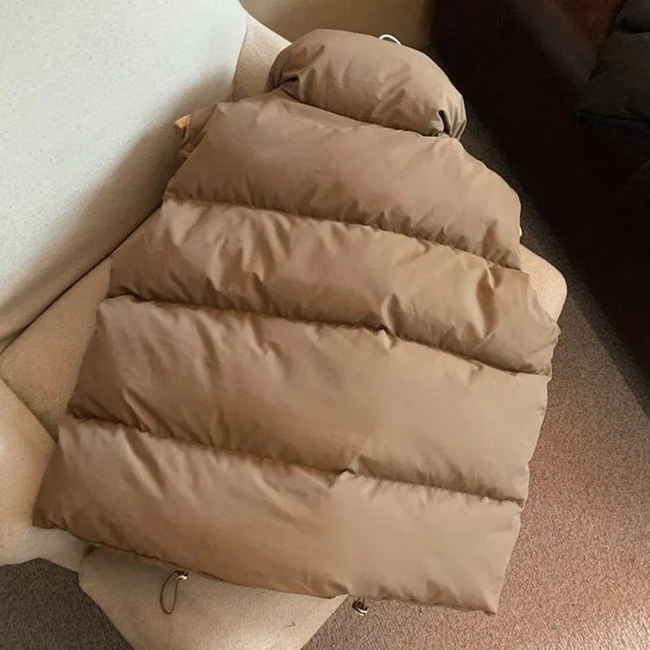 "Varm kvinnlig dunväst i beige, vindtät och stilren, perfekt för kyligt väder, kombinerar elegans med funktionalitet."