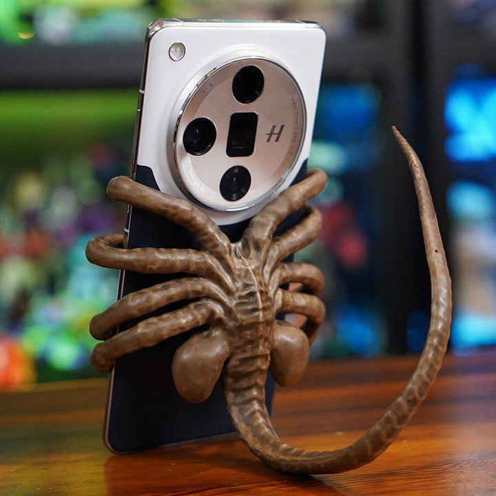 Alienformad telefonhållare i grön harts, passar alla smartphones; justerbar svans för stabilitet. Perfekt som present.