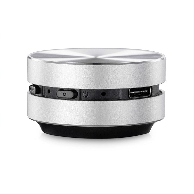 "Bärbar benledning Bluetooth-högtalare, kompakt och rund design, silverfärgad med grå detaljer, lätt att ta med."