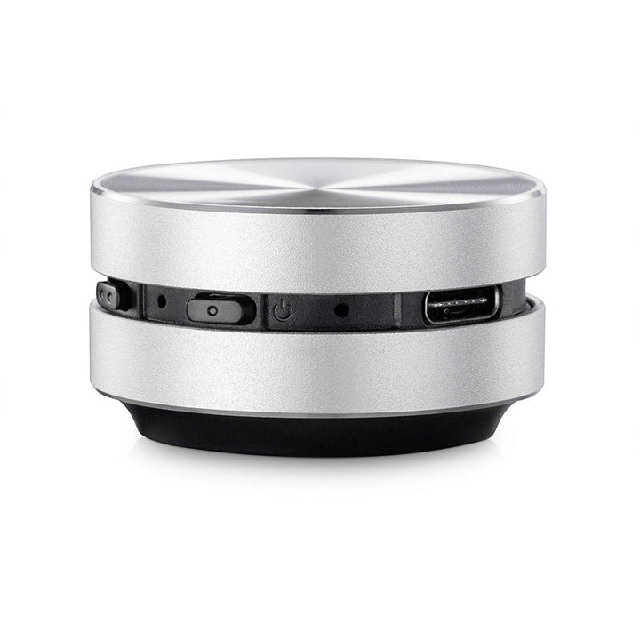 "Bärbar benledning Bluetooth-högtalare, kompakt och rund design, silverfärgad med grå detaljer, lätt att ta med."