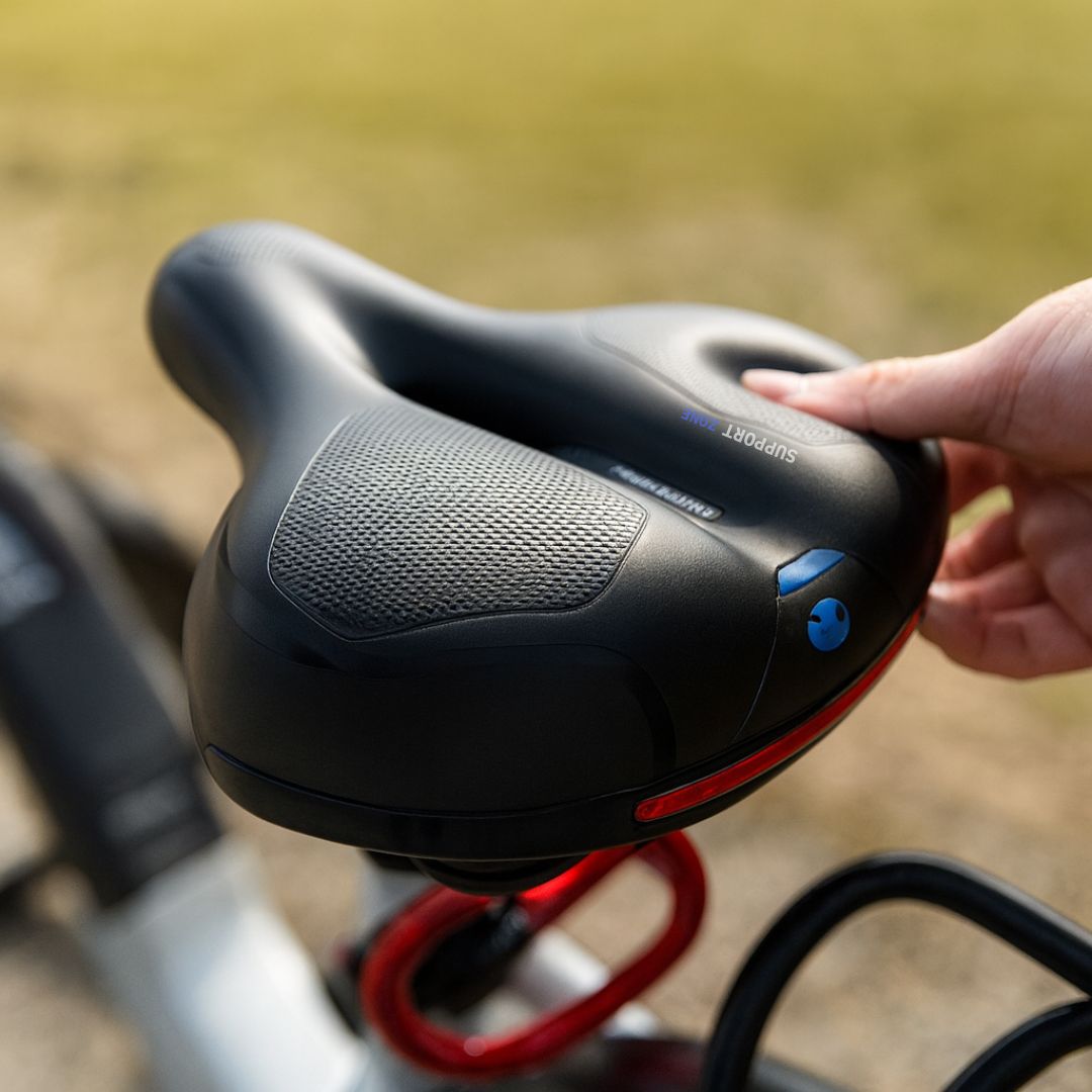 Svart cykelsadel med röd accent, ergonomisk och fjädrad för långa turer.