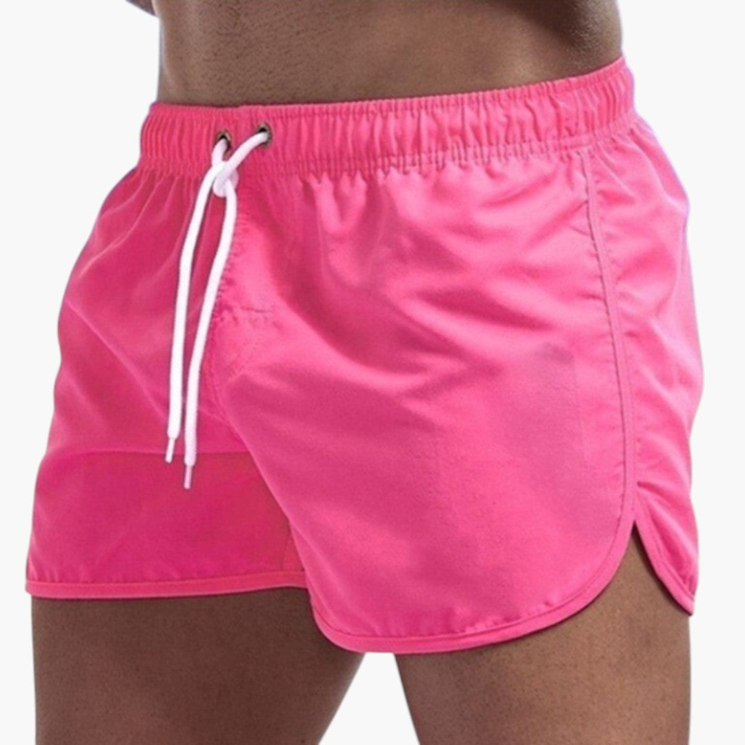 Man bär färgstarka herrbadshorts med justerbar dragsko. Perfekta badkläder för strand, pool & sommarfritid.