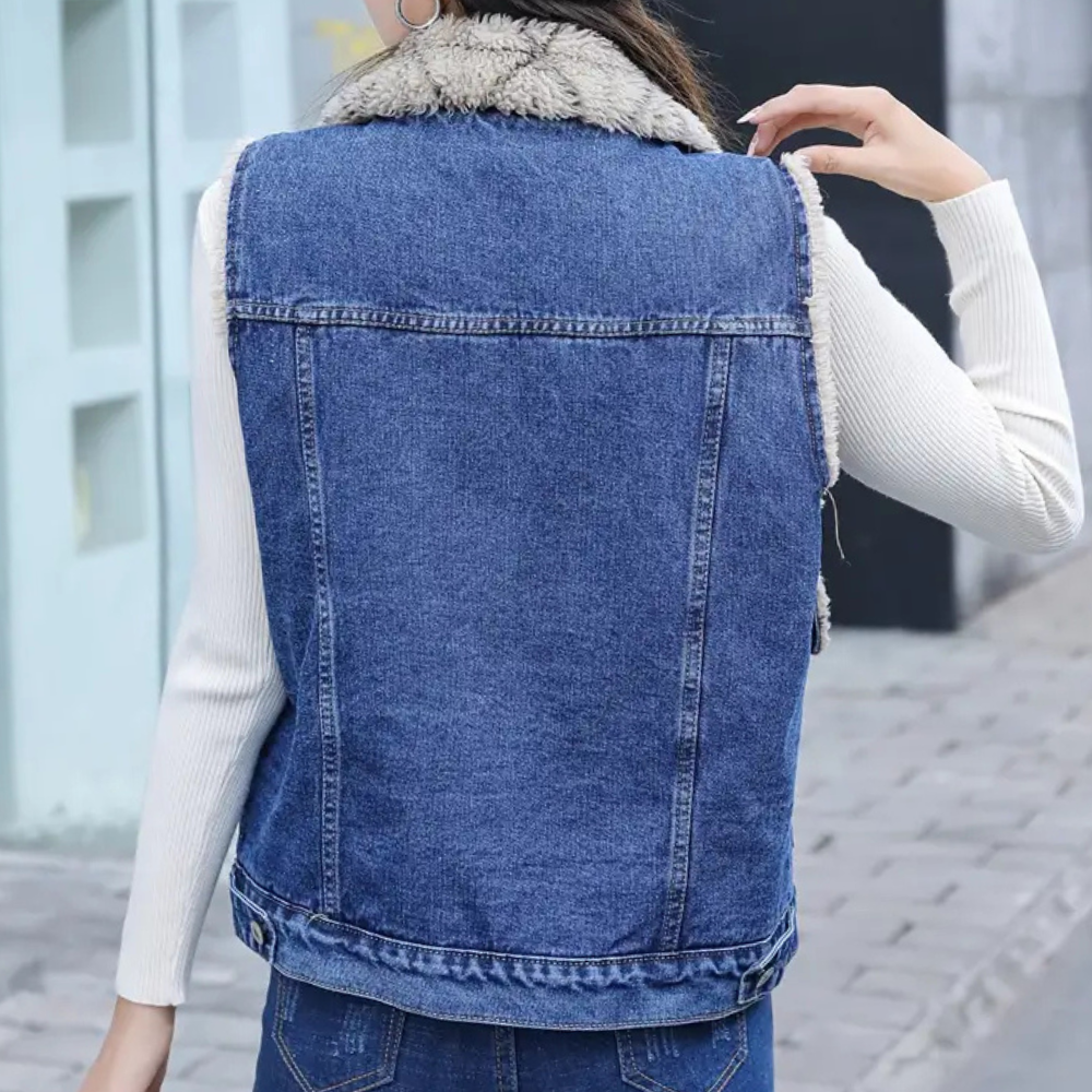 Kvinna bär blå höstväst med tröja, snyggt lagerplagg. Elegant och varm damväst för mode.