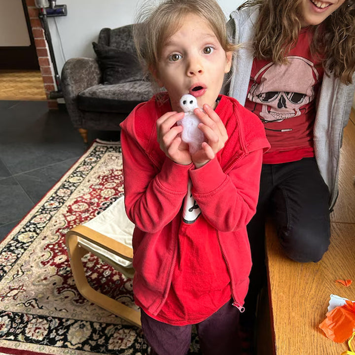 "Charmig handgjord filttom med unika detaljer, perfekt för Halloweendekoration, vilande i svart silkespapper."