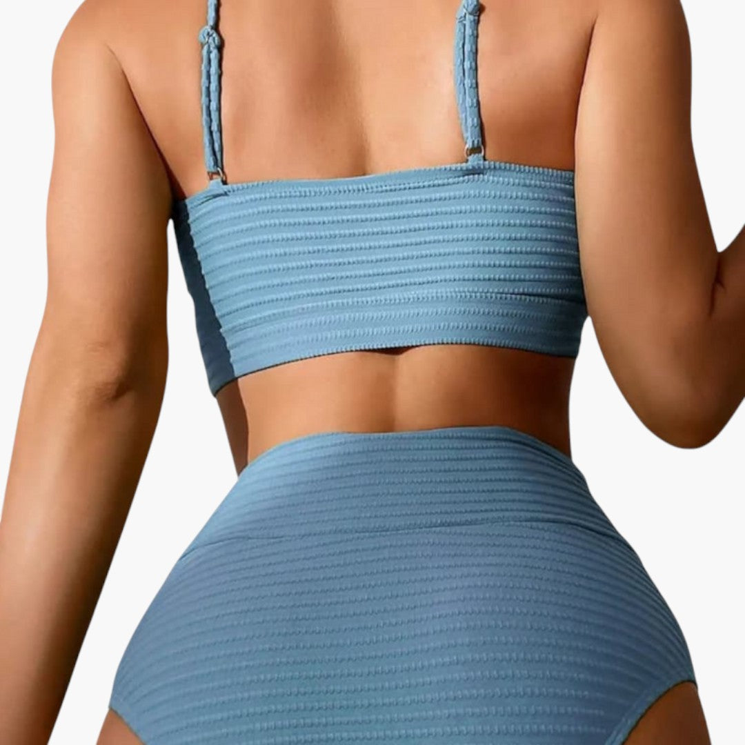 Kvinna bär tvådelad bikini med hög midja & trekantstopp. Elegant sommarstil, moderna strandkläder.