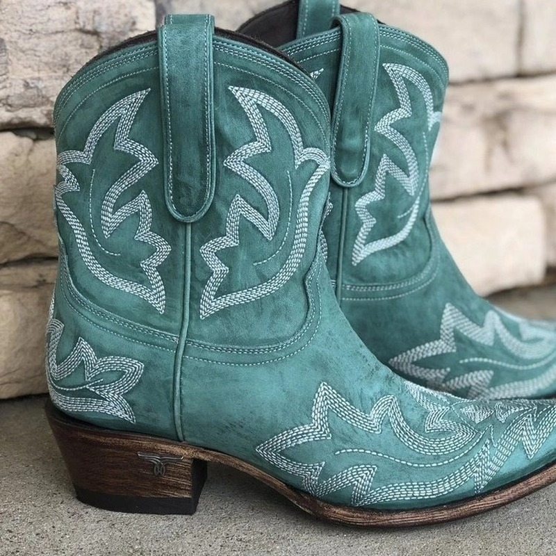 Fullängdsbild av trendiga broderade cowboystövlar i elegant västernstil. Korta damstövlar för höstens mode.