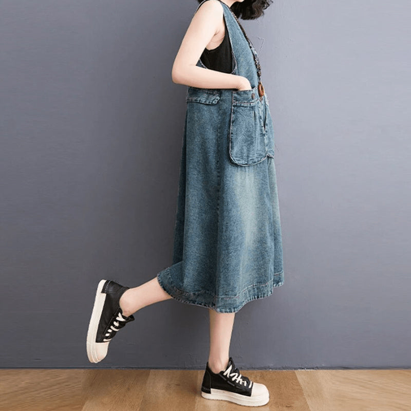 "Dam denim overallklänning med breda axelband och sidfickor, ärmlös design i jeansmaterial för stil och komfort."
