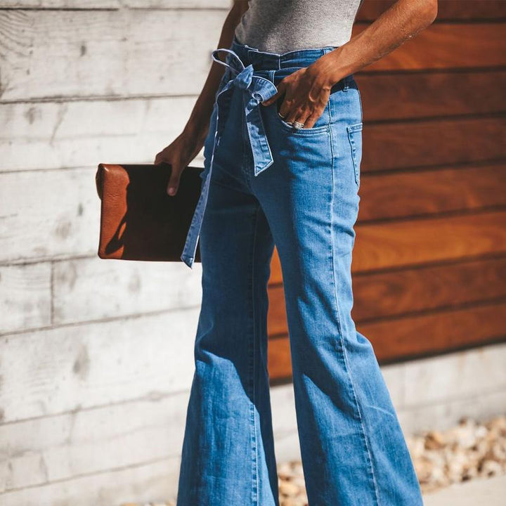 "Dambyxor i blå denim med hög midja och vida ben, ses med bälte för justerbar passform, eleganta och tidlösa."