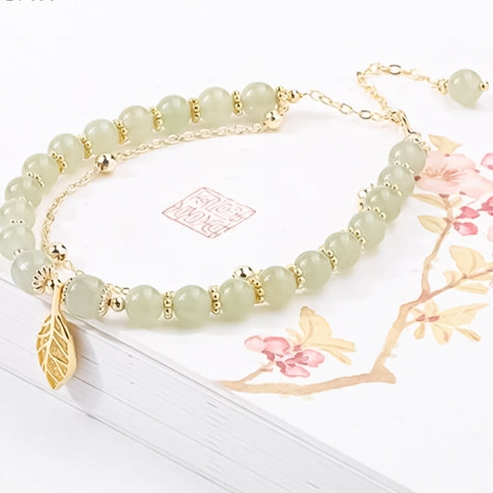 "Dame armband i grön jade med gulddekor, elegant smycke, grön sten och gyllene detaljer, perfekt accessoar för kvinnor."