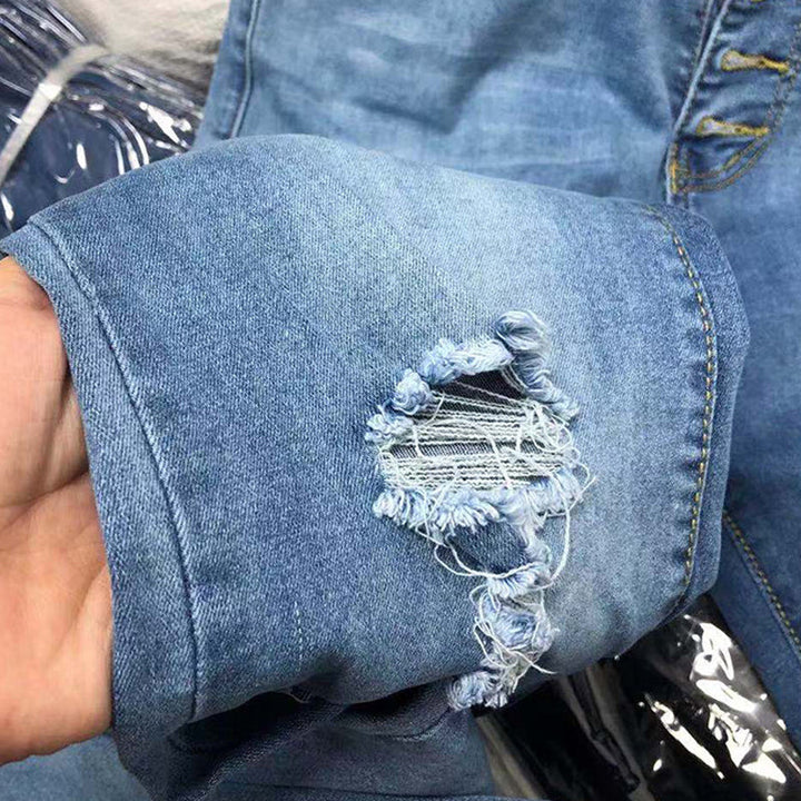 "Damer höga midja mörkblå slitna jeans med femknappar, visar subtila slitdetaljer för en modern och stilren look."