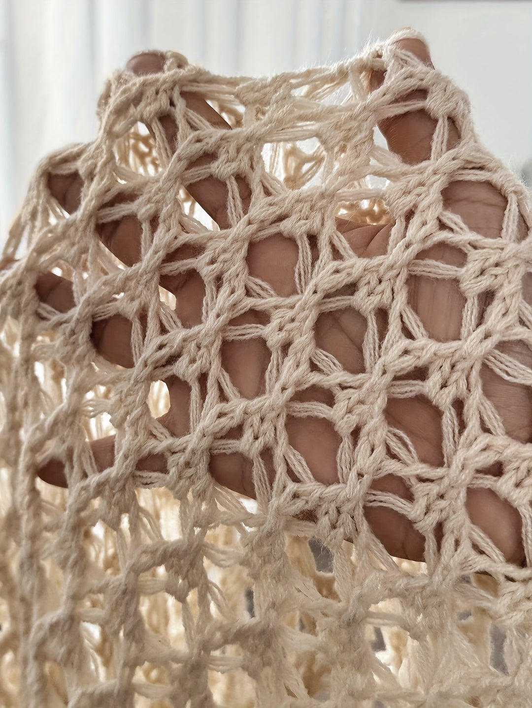 Beige damkofta med modern drapering, fotograferad framifrån, utmärkt för avslappnad elegans.