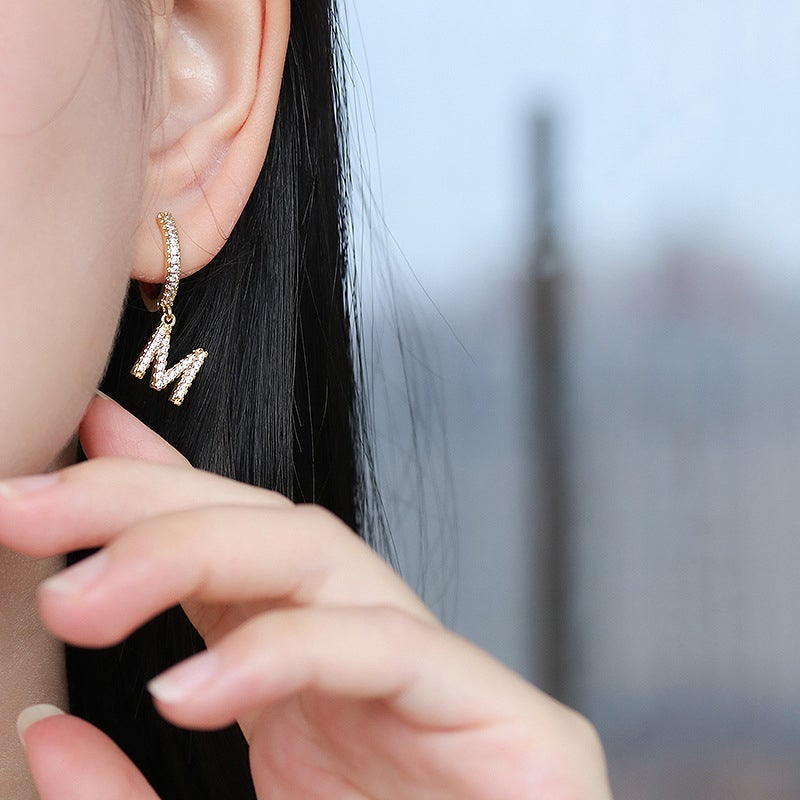 "Damhalsband i alfabetdesign med kubisk zirkon, elegant glansig finish, perfekt accessoar, visas i silver eller gyllene."