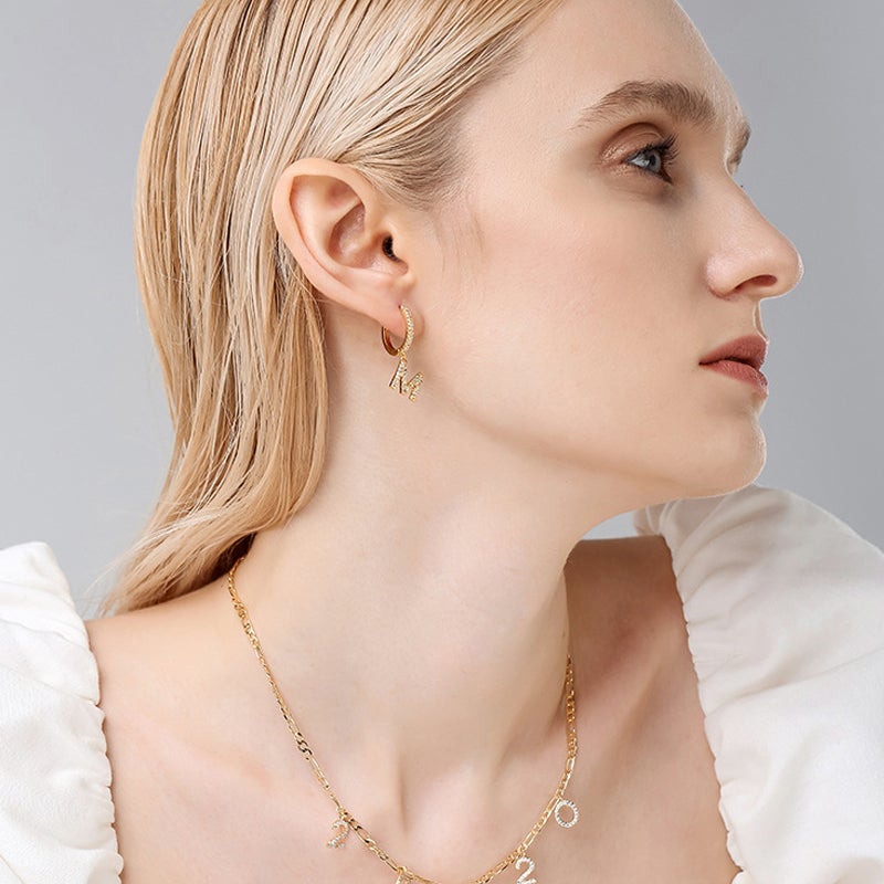 "Damhalsband i alfabetdesign med kubisk zirkon, elegant glansig finish, perfekt accessoar, visas i silver eller gyllene."