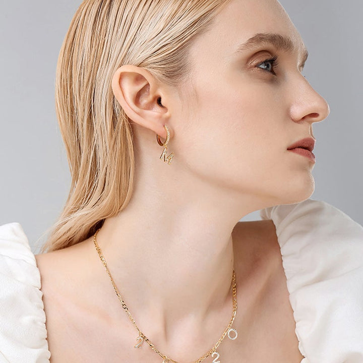 "Damhalsband i alfabetdesign med kubisk zirkon, elegant glansig finish, perfekt accessoar, visas i silver eller gyllene."