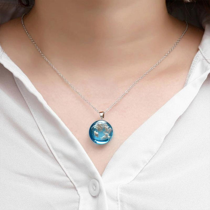 "Damhalsband i harts med blå himmel och vita moln, hjärtformad design, justerbar guldkedja 45 cm, elegant accessoar."