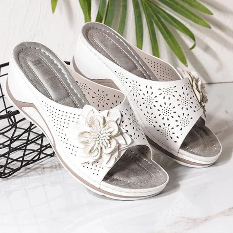 "Damsandaler med ihåliga snidade kilklackar, beige färg, öppen tå och blommiga detaljer för modern stil och komfort."