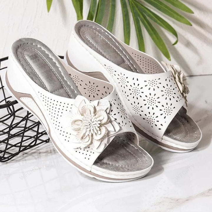 "Damsandaler med ihåliga snidade kilklackar, beige färg, öppen tå och blommiga detaljer för modern stil och komfort."