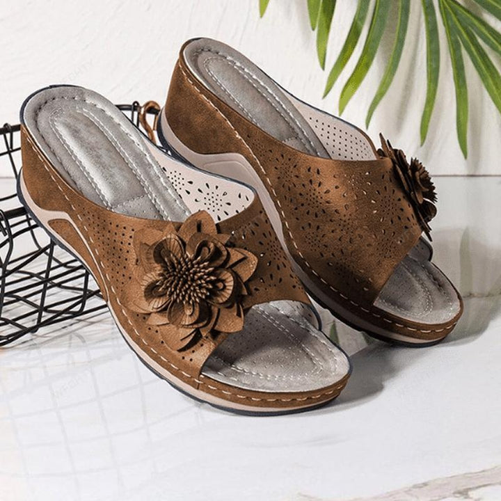 "Damsandaler med ihåliga snidade kilklackar, beige färg, öppen tå och blommiga detaljer för modern stil och komfort."