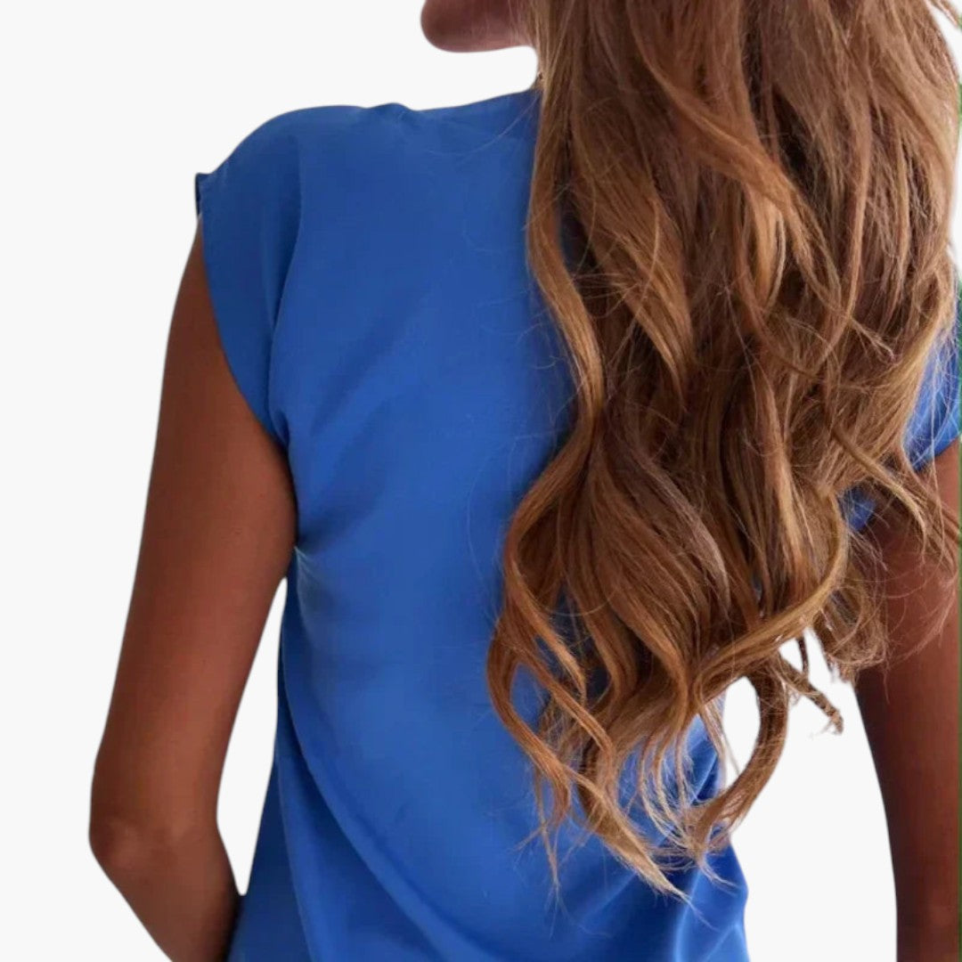 Enfärgad damtopp med stilren V-ringning och capärmar. Perfekt basplagg för en elegant & bekväm look.