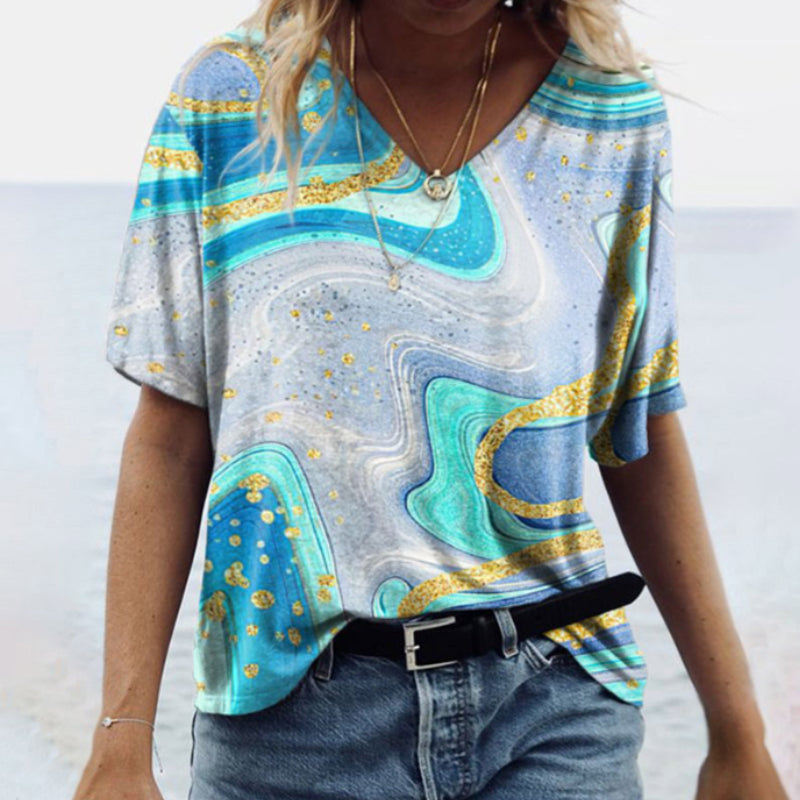 "Damtopp med sommarmarmortryck, V-ringning och utsvängd fåll, perfekt för stranddagar och vardagslook."