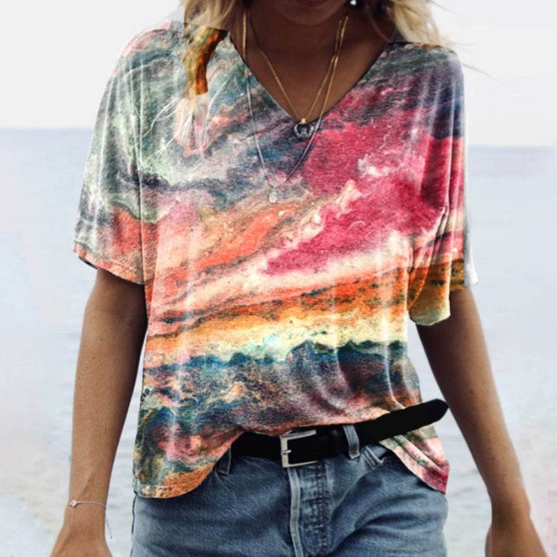 "Damtopp med sommarmarmortryck, V-ringning och utsvängd fåll, perfekt för stranddagar och vardagslook."