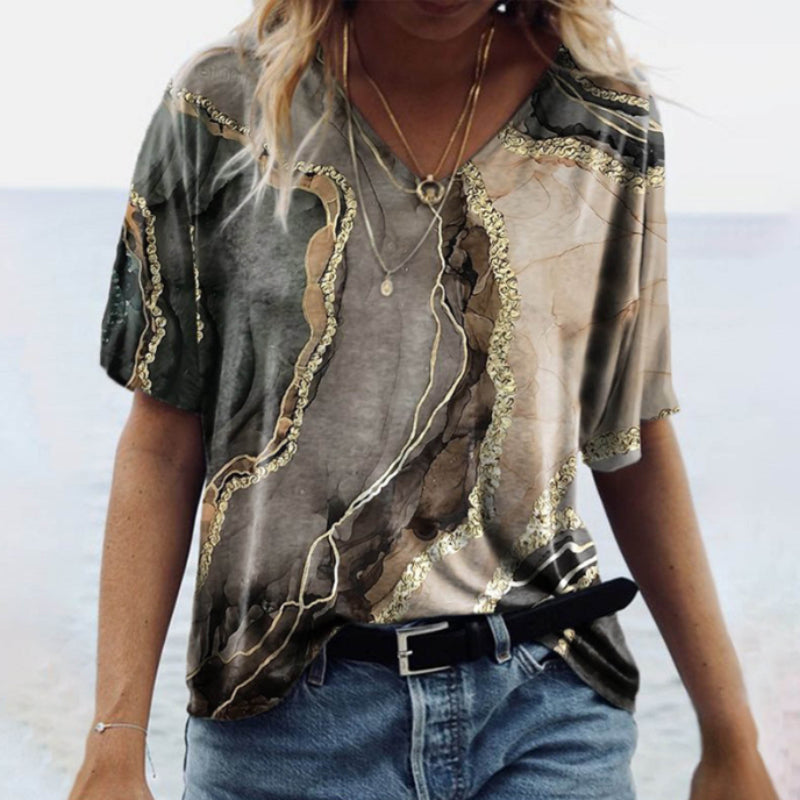 "Damtopp med sommarmarmortryck, V-ringning och utsvängd fåll, perfekt för stranddagar och vardagslook."