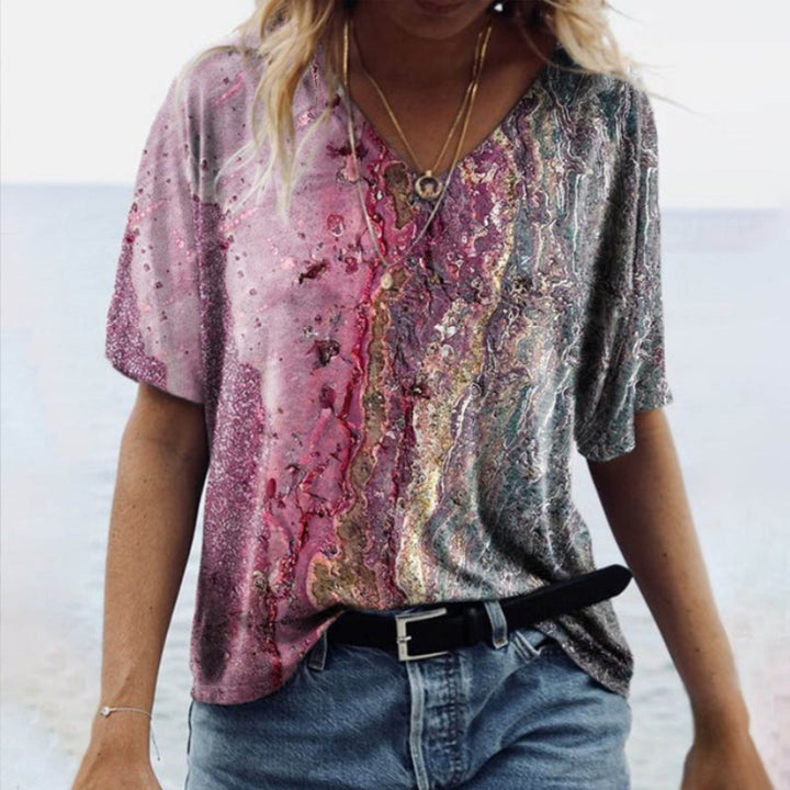 "Damtopp med sommarmarmortryck, V-ringning och utsvängd fåll, perfekt för stranddagar och vardagslook."