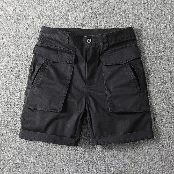 En översikt av beiga taktiska cargoshorts med praktiska fickor, presenterade på en enfärgad bakgrund.