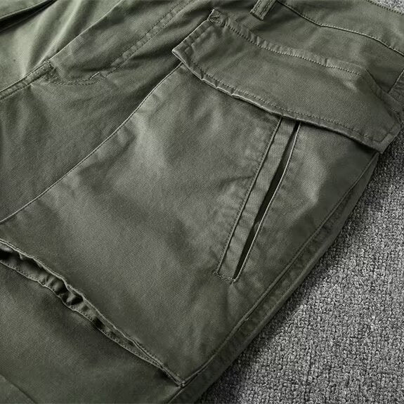Livsstilsfotografi av en man som bär beiga taktiska cargoshorts, redo för utomhusaktiviteter, sommarshorts.