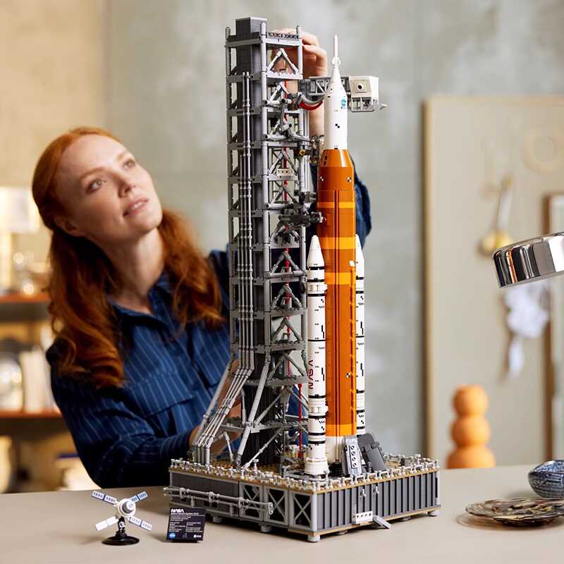 Närbild på händerna som bygger en NASA Artemis raket modellkit, visar den detaljerade byggprocessen.