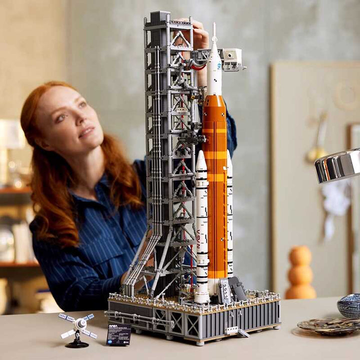 Närbild på händerna som bygger en NASA Artemis raket modellkit, visar den detaljerade byggprocessen.