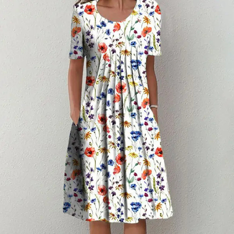 "Elegant blommig A-linje sommarklänning med rund hals i vitt, blått och gult, perfekt för sommardagar och fester."