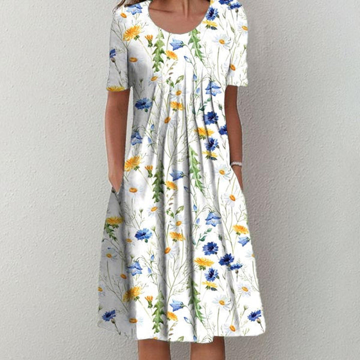 "Elegant blommig A-linje sommarklänning med rund hals i vitt, blått och gult, perfekt för sommardagar och fester."