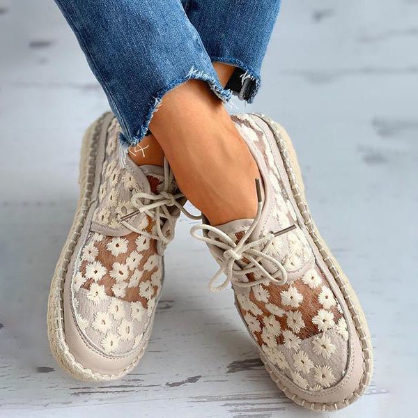 Kvinnlig modell bär vita broderade sneakers som matchar en avslappnad outfit, framhäver bekvämlighet
