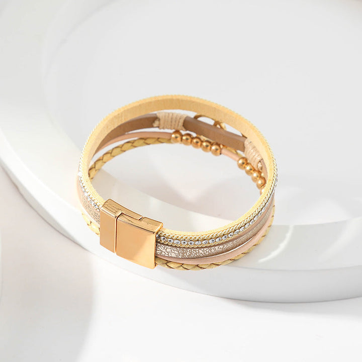 Elegant damarmband i läder, flera lager, dekorerat med guldpärlor för sofistikerad stil och justerbar komfort.
