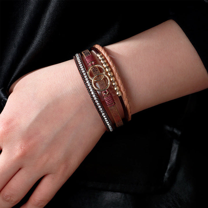 Elegant damarmband i läder, flera lager, dekorerat med guldpärlor för sofistikerad stil och justerbar komfort.