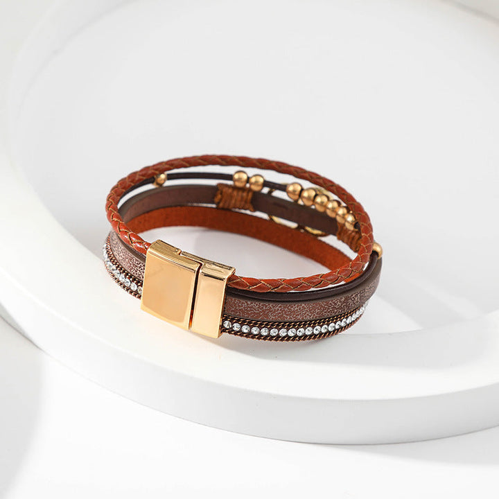 Elegant damarmband i läder, flera lager, dekorerat med guldpärlor för sofistikerad stil och justerbar komfort.