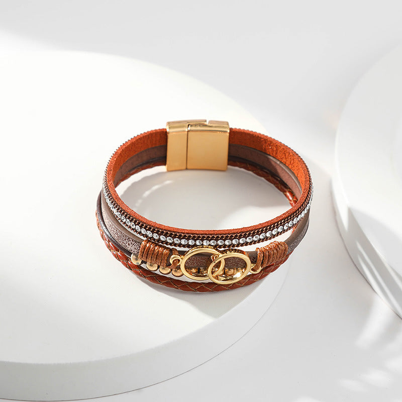 Elegant damarmband i läder, flera lager, dekorerat med guldpärlor för sofistikerad stil och justerbar komfort.