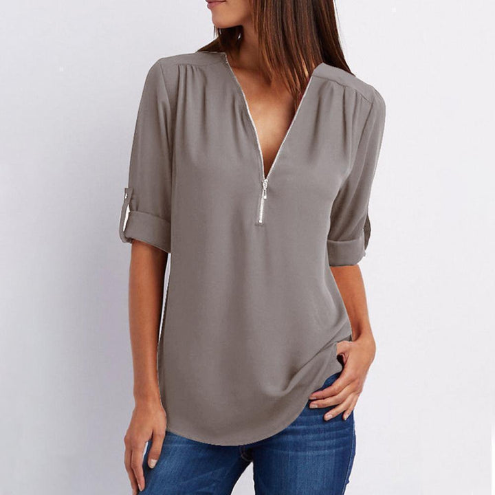 "Elegant damblusa med V-ringning och justerbar dragkedja, finns i flera färger; perfekt för stil och komfort."
