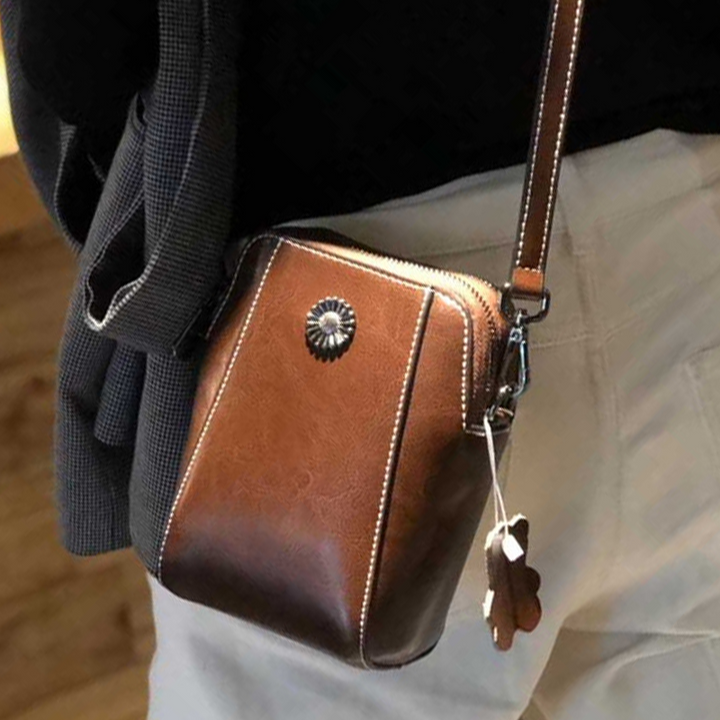 "Elegant damkurirväska i oljevaxat äkta läder, tidlös design, justerbar rem, perfekt för både vardags- och formella kläder."