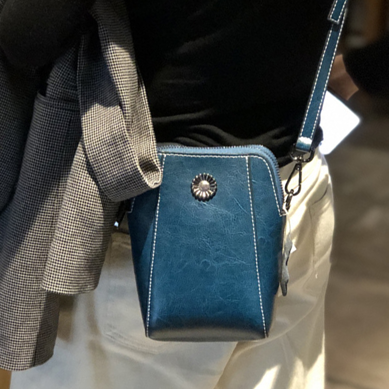 "Elegant damkurirväska i oljevaxat äkta läder, tidlös design, justerbar rem, perfekt för både vardags- och formella kläder."