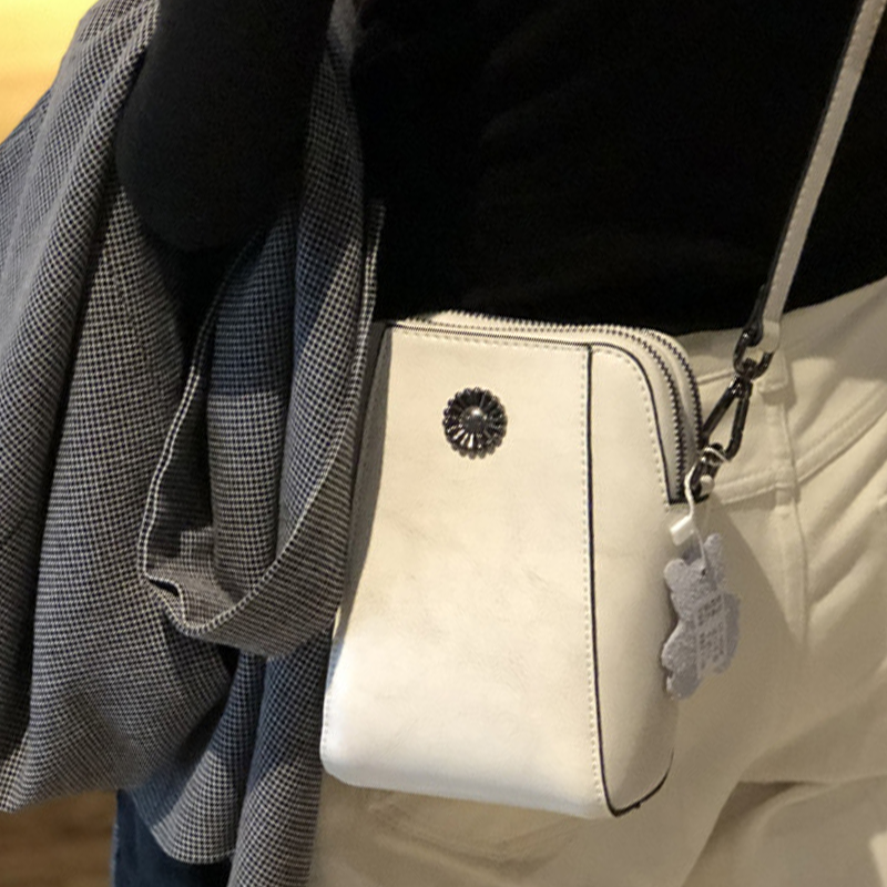 "Elegant damkurirväska i oljevaxat äkta läder, tidlös design, justerbar rem, perfekt för både vardags- och formella kläder."