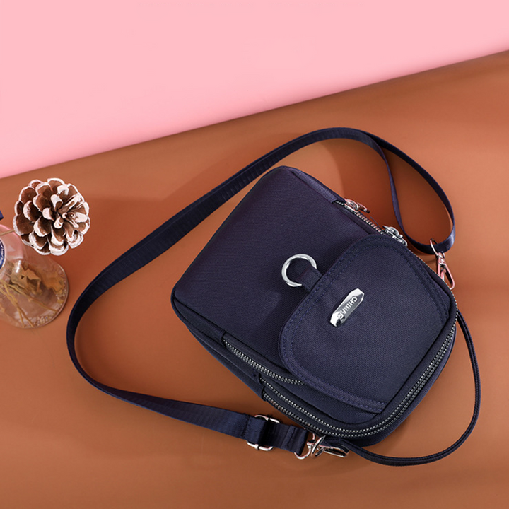 "Elegant damväska i vattentätt nylon med flera fickor, justerbar rem, perfekt för dagligt bruk och resor."